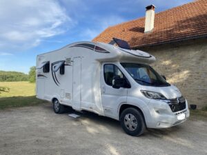 Camping-car moderne stationné près d'une bâtisse rurale