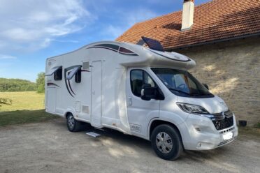 Camping-car moderne stationné près d'une bâtisse rurale
