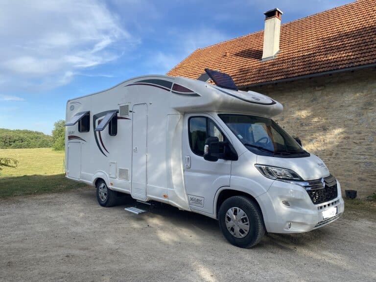 Camping-car moderne stationné près d'une bâtisse rurale
