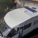Camping-car blanc avec panneau solaire sur le toit.