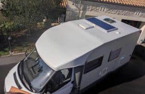 Camping-car blanc avec panneau solaire sur le toit.