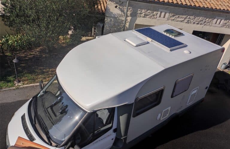 Camping-car blanc avec panneau solaire sur le toit.