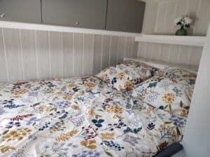 Linge de lit fleuri et armoire grise en bois.