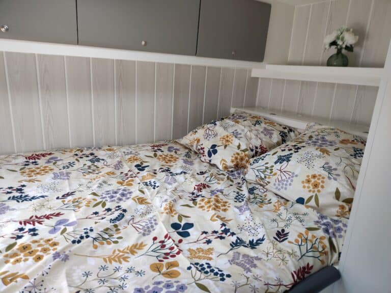 Linge de lit fleuri et armoire grise en bois.
