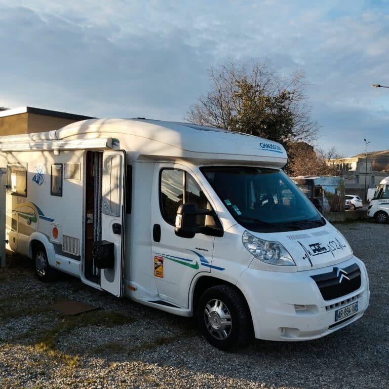 Camping-car blanc stationné en journée.