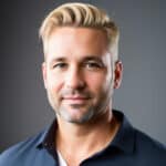 Homme souriant, cheveux blonds, barbe, chemise bleue.