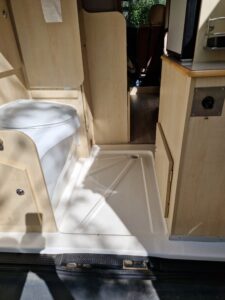 Intérieur de camping-car avec sièges et toilettes portables.