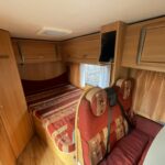Intérieur cosy de caravane avec lits et rangements bois.