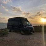 Fourgon aménagé au coucher de soleil en bord de mer.