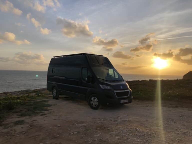 Fourgon aménagé au coucher de soleil en bord de mer.