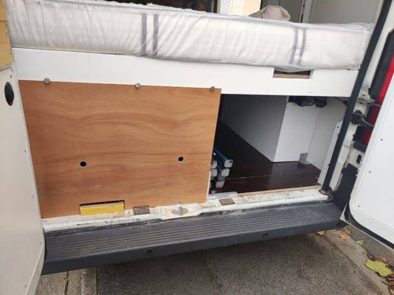 Matelas et rangements dans camionnette aménagée.