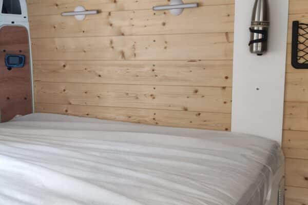 Camper-Interieur, gemütliches Bett, Wand aus Kiefernholz.