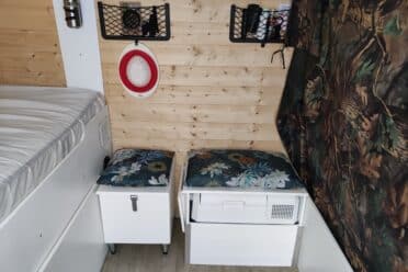 Intérieur de caravane, lit et rangements boisés.