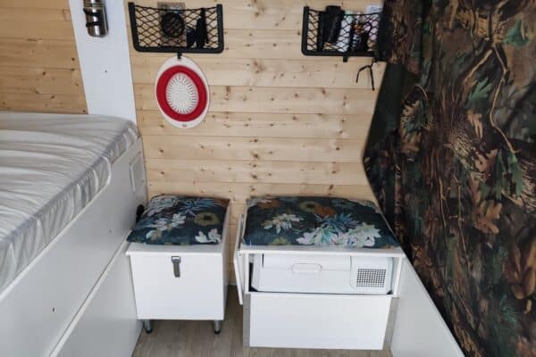 Innenausstattung eines Wohnwagens, Bett und Stauraum aus Holz.
