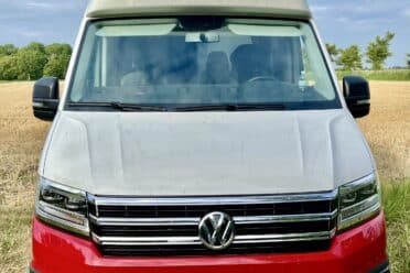 Fourgon Volkswagen rouge et blanc dans un champ.