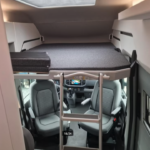 Intérieur cabine camping-car avec couchette et sièges.