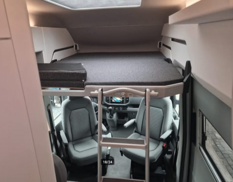Intérieur cabine camping-car avec couchette et sièges.