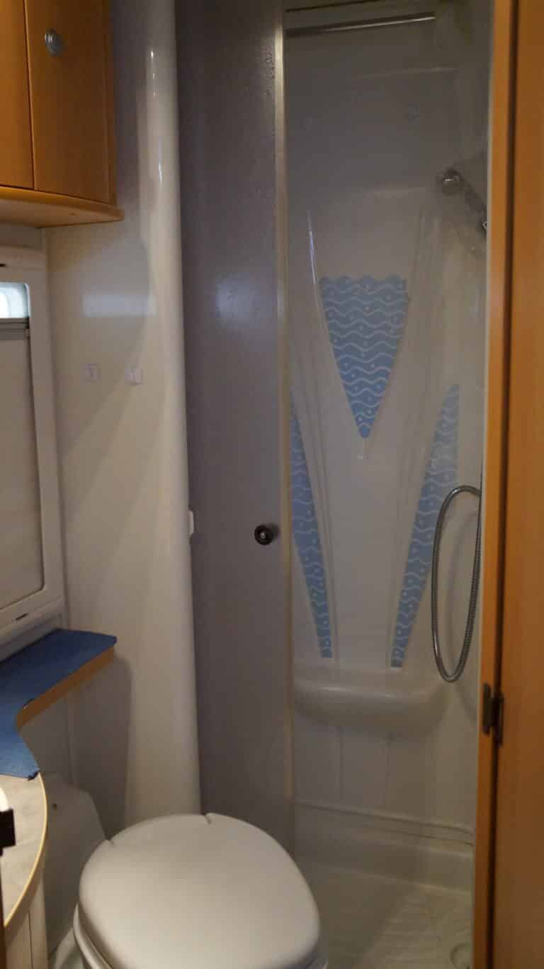 Salle de bain compacte moderne avec douche et toilettes.