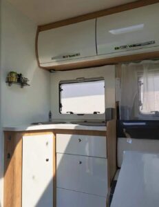 Intérieur moderne de camping-car avec cuisine et rangements.