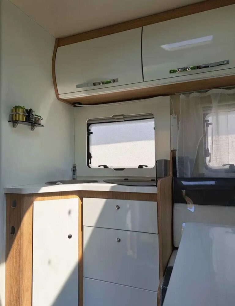 Intérieur moderne de camping-car avec cuisine et rangements.