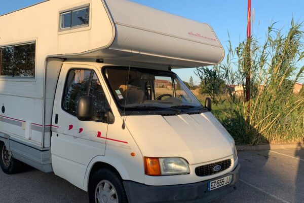 Camping-car blanc stationné au coucher du soleil