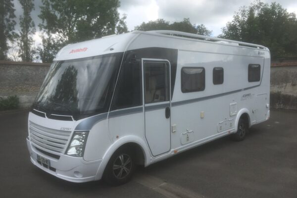 Camping-car blanc moderne stationné à l'extérieur.