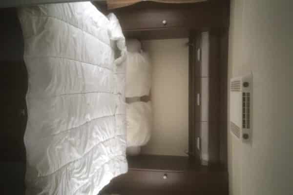 Lit blanc dans une chambre épurée et moderne.