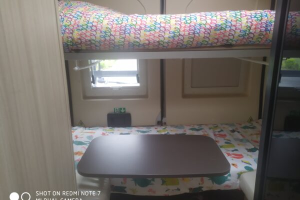 Intérieur de caravane avec lits superposés et table.