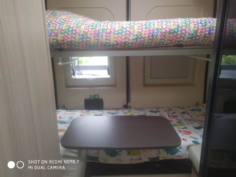 Intérieur de caravane avec lits superposés et table.
