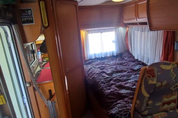 Intérieur cosy de camping-car avec lit et cuisine.