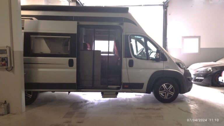 Camping-car blanc dans un garage éclairé.