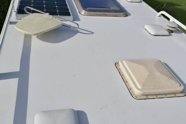 Panneau solaire et écoutilles sur toit de véhicule.