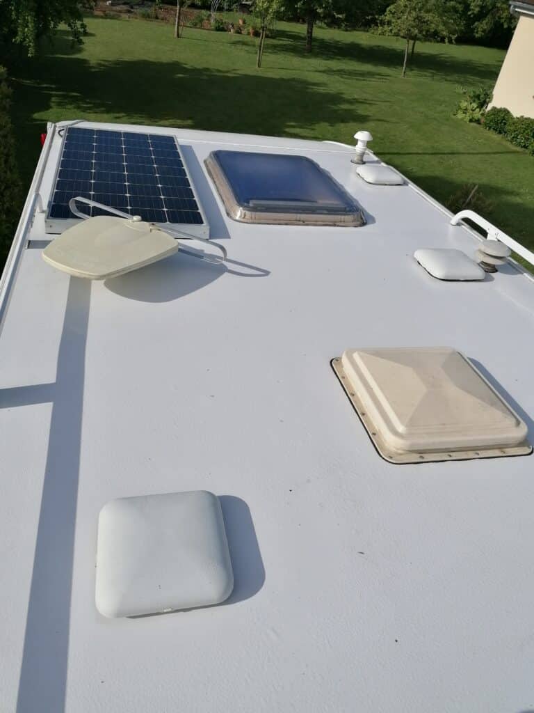 Panneau solaire et écoutilles sur toit de véhicule.