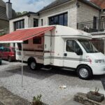 Camping-car blanc avec auvent déployé.