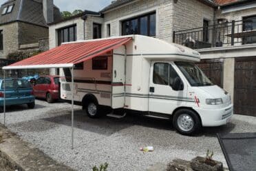 Camping-car blanc avec auvent déployé.