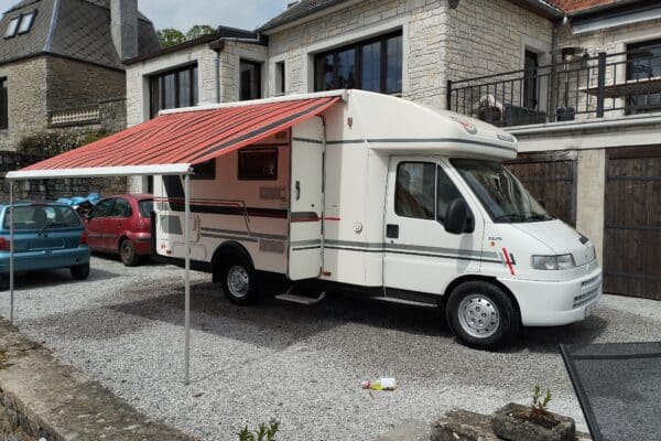Wohnmobil weiß mit ausgeklapptem Vordach.
