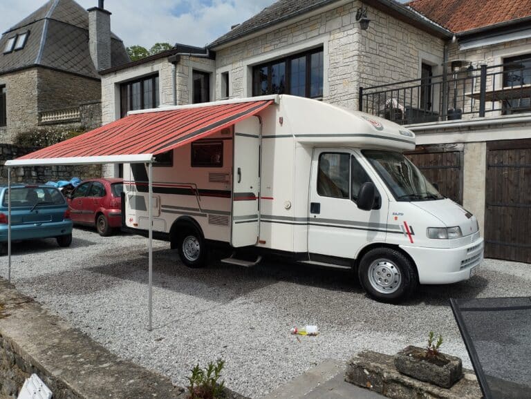 Camping-car blanc avec auvent déployé.