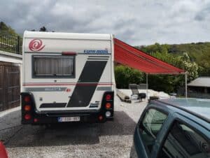 Camping-car avec auvent déployé et chien.