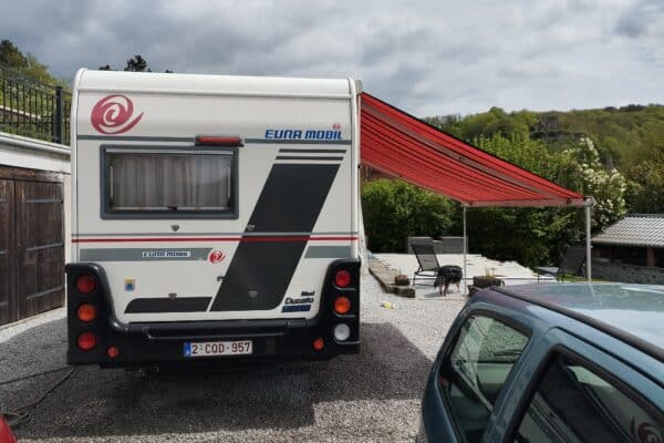 Wohnmobil mit ausgeklapptem Vorzelt und Hund.