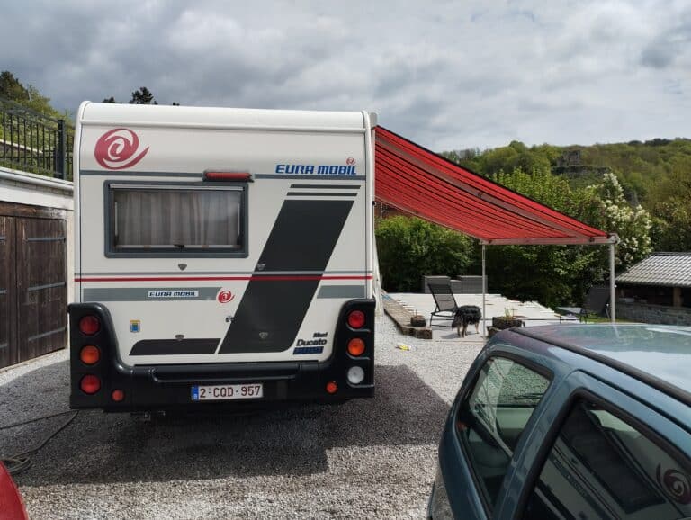 Camping-car avec auvent déployé et chien.