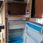 Réfrigérateur ouvert avec micro-ondes intégré en camping-car.