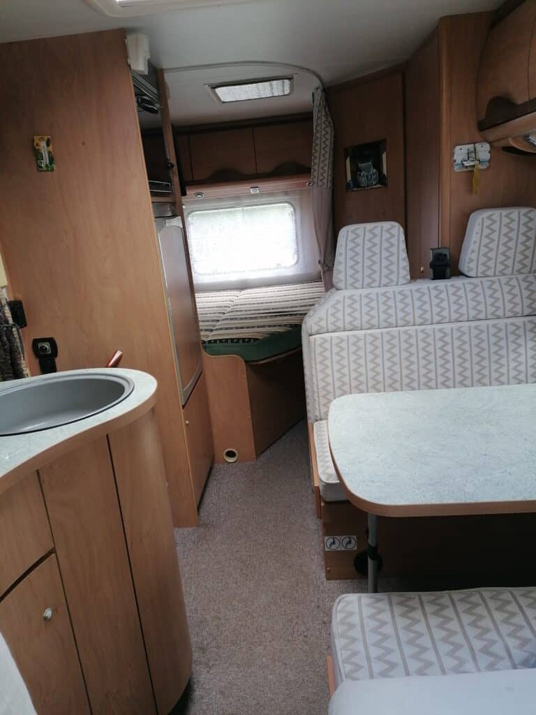 Intérieur confortable de camping-car avec lits et cuisine équipée.