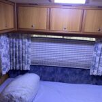 Chambre intérieure de camping-car avec lit et placards.