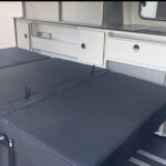 Intérieur moderne de camping-car avec cuisine et lit.