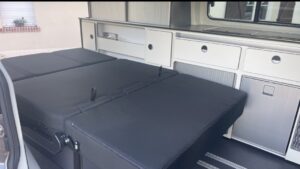 Intérieur moderne de camping-car avec cuisine et lit.