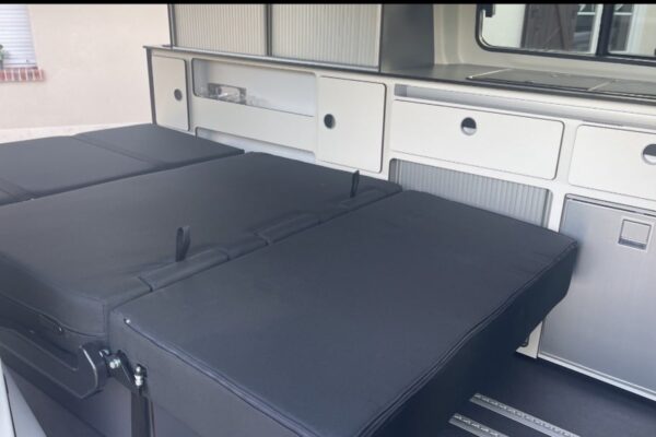 Intérieur moderne de camping-car avec cuisine et lit.