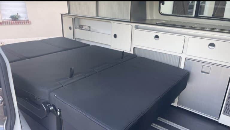 Intérieur moderne de camping-car avec cuisine et lit.