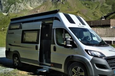 Camping-car moderne devant montagnes pittoresques.