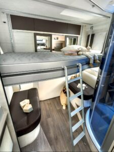 Intérieur moderne de camping-car avec lits superposés et cuisine.