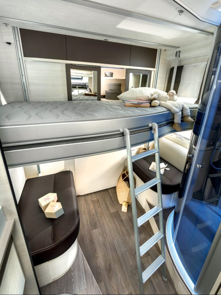 Intérieur moderne de camping-car avec lits superposés et cuisine.